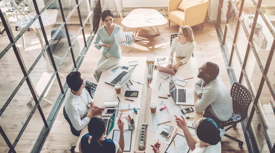 A diverse team collaborating in a modern office, discussing ideas around a large table.