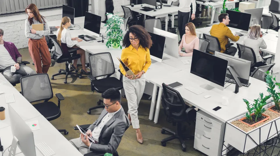 Modern office workspace with diverse employees collaborating and working at desks.