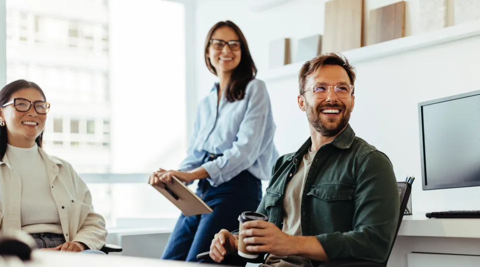 Smiling colleagues in a modern office, engaged in a friendly conversation with casual attire.