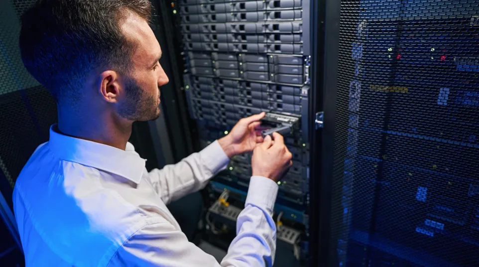 Technician installing a server component in a data center with blue lighting effect.