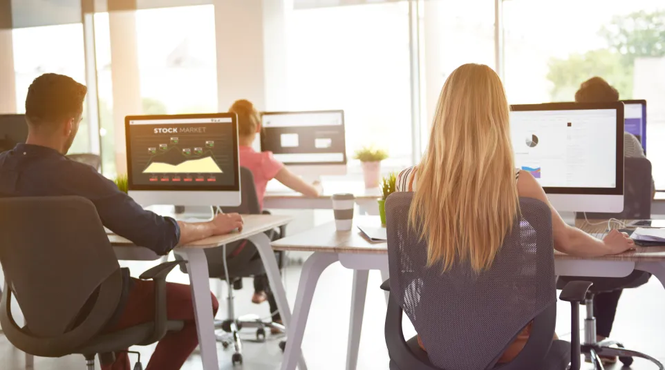 a group of people sitting at a table with computers