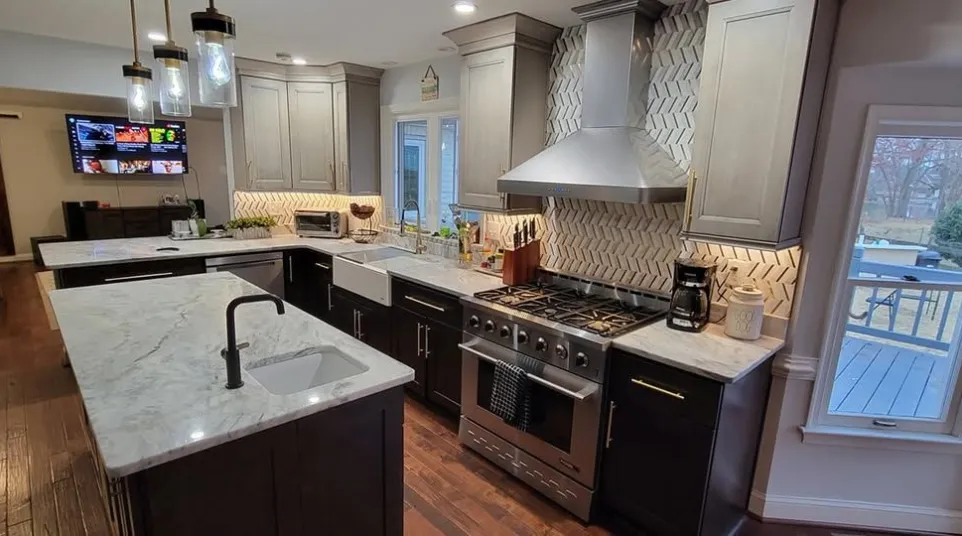 Modern kitchen with marble countertops, dark cabinets, white tile backsplash, stainless appliances, and hardwood floors.