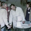 a group of people standing around a table with a white object on it