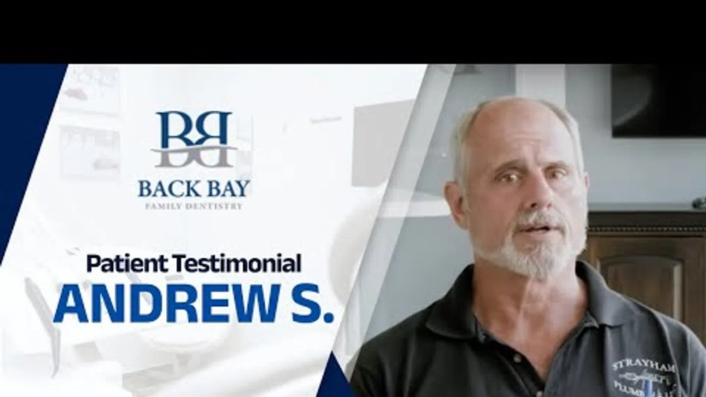 Middle-aged man giving a patient testimonial for Back Bay Family Dentistry with dental office background.