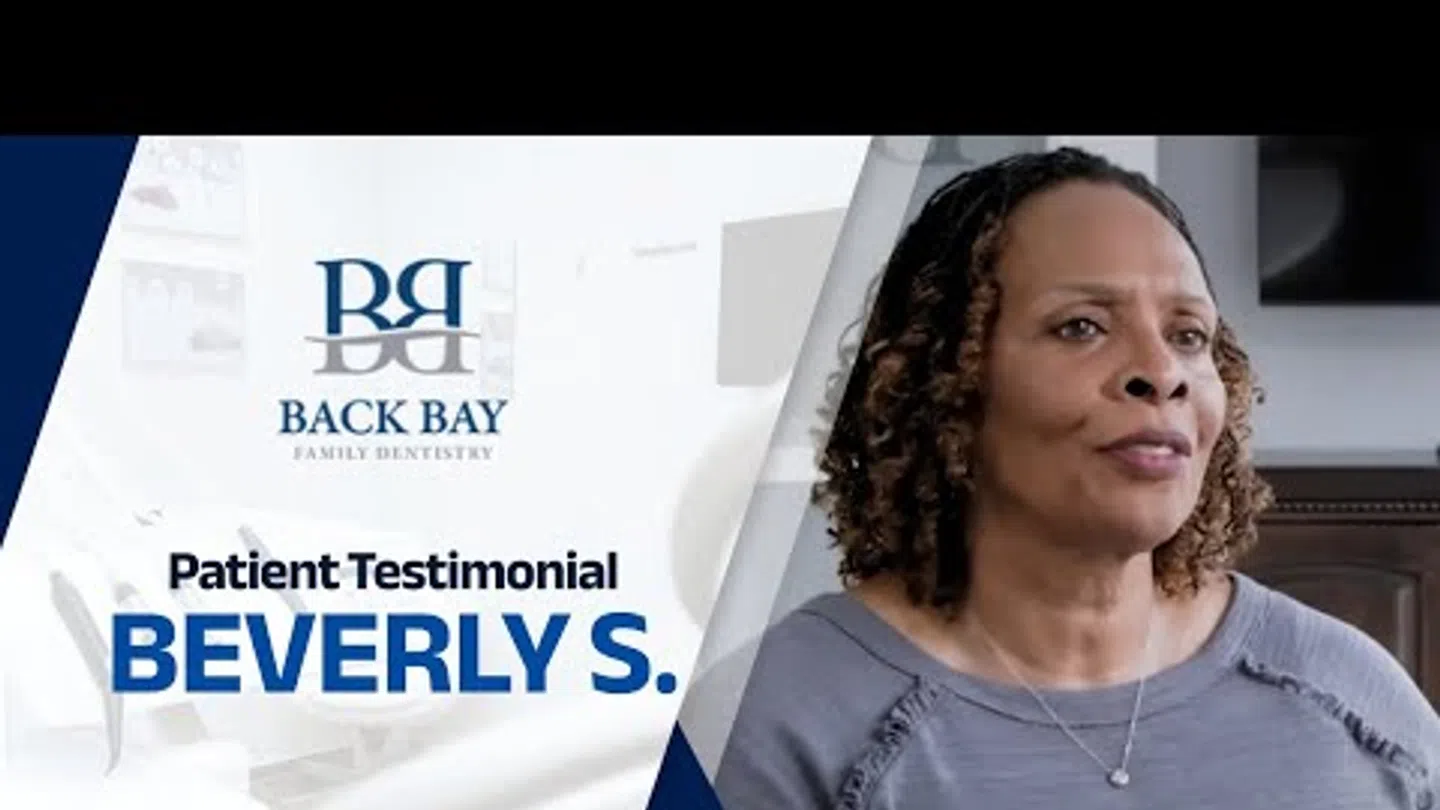 Back Bay Family Dentistry patient Beverly S. shares her testimonial in a clinical setting with dental branding.