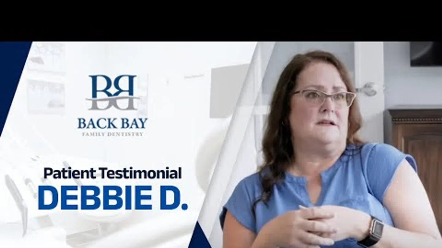 Patient testimonial from Debbie D. at Back Bay Family Dentistry with woman in blue shirt speaking.