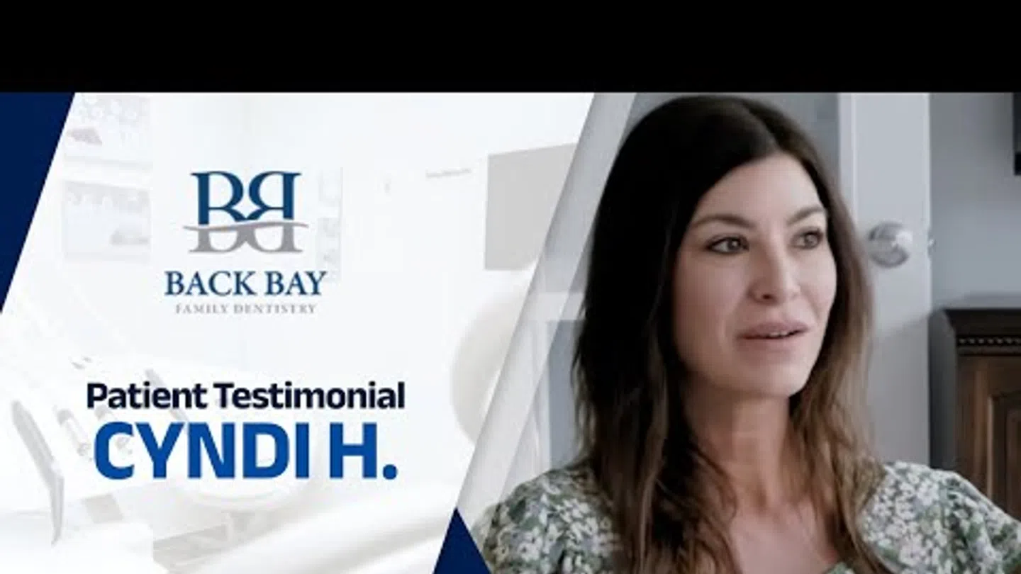 Woman sharing her patient testimonial for Back Bay Family Dentistry with logo and text on screen.