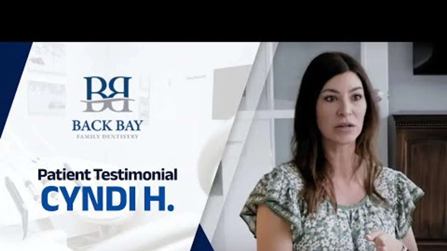 Woman giving a patient testimonial for Back Bay Family Dentistry in a calm indoor setting.