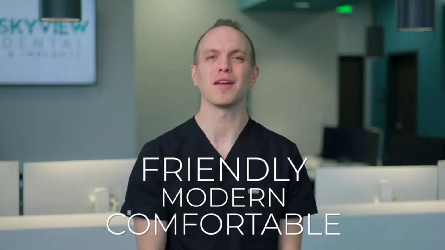 Male dental professional in black scrubs at modern clinic with words friendly, modern, comfortable overlayed.