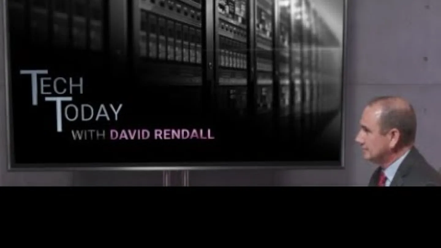 Man in suit watching Tech Today with David Rendall episode featuring server racks on screen.