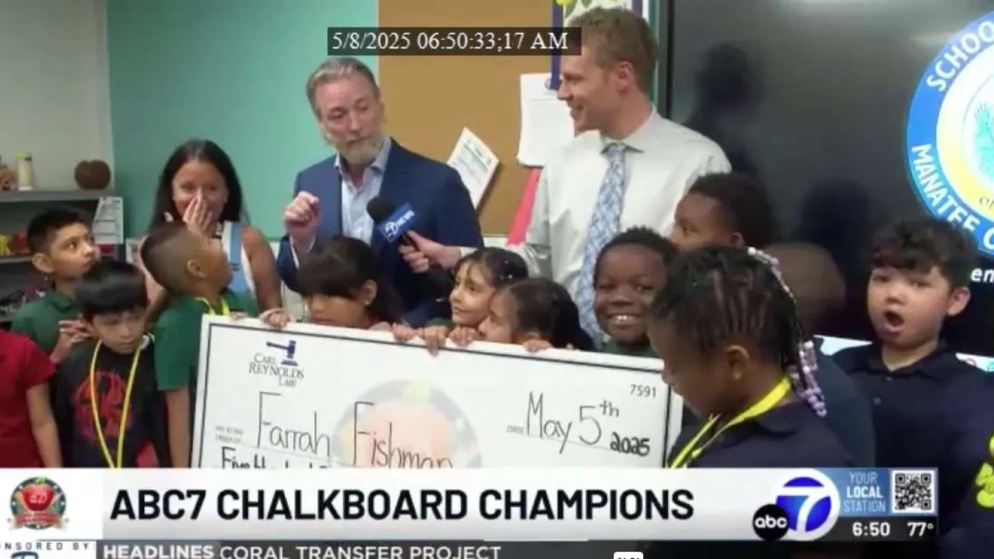 Diverse group of children and adults holding a large check at ABC7 Chalkboard Champions event in school setting.