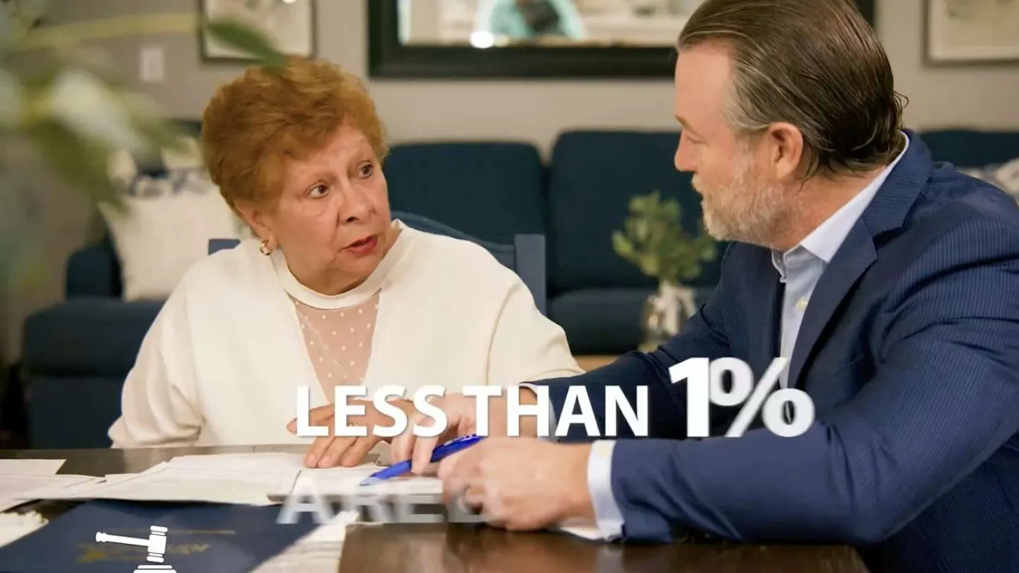 Older woman and man in suit discuss documents at a table with text less than 1 percent.