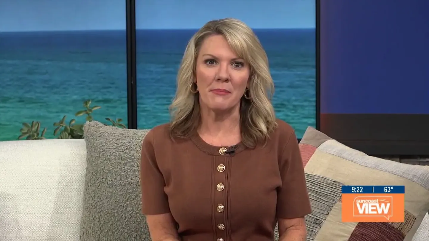 Blonde woman in brown buttoned shirt sitting on a couch with ocean view background and Suncoast View logo.