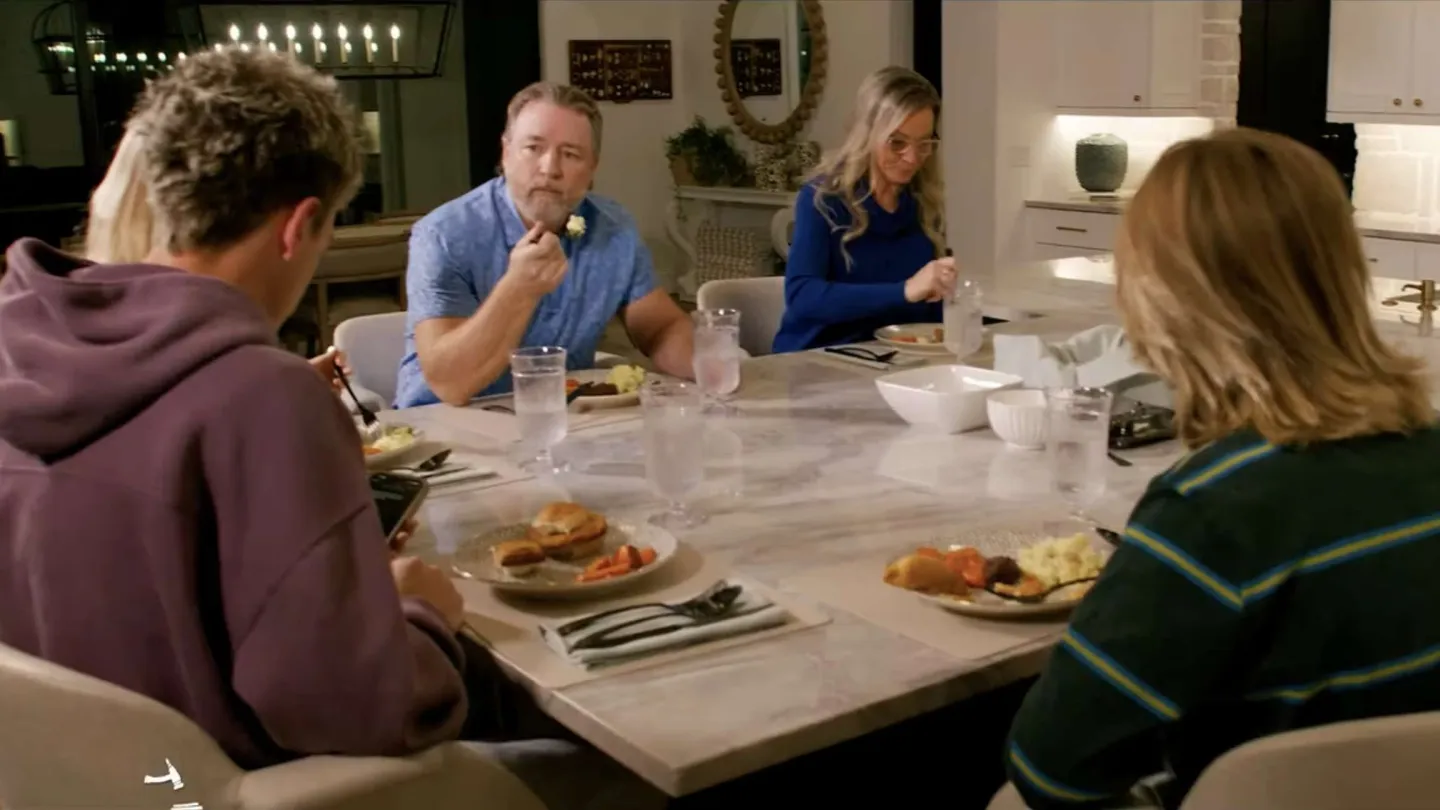 Family of six eating dinner together at a marble kitchen island in a modern home setting