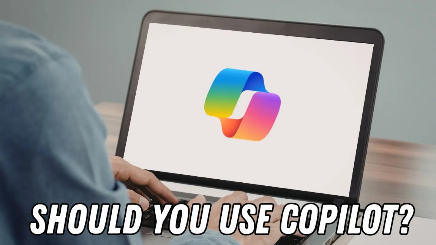 Person using laptop displaying colorful Microsoft Copilot logo with text Should You Use Copilot underneath.