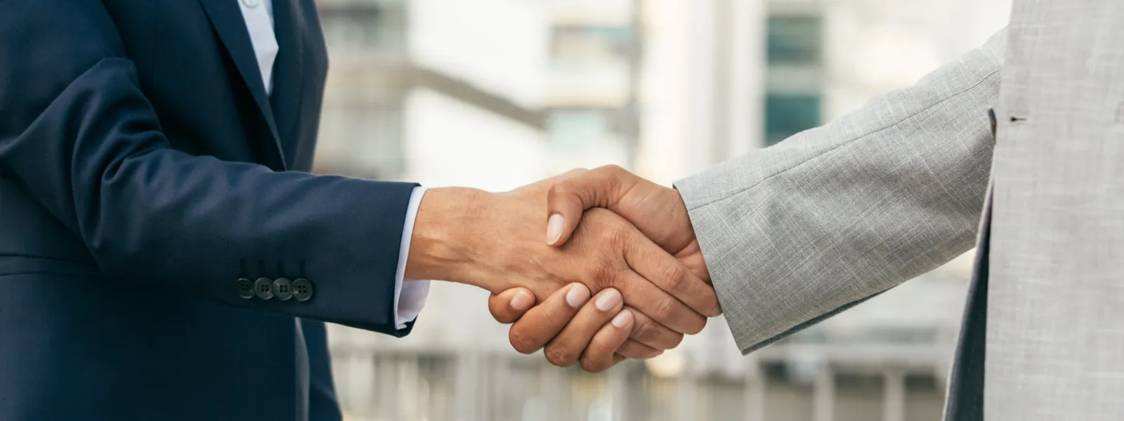 two business men shaking hands outside