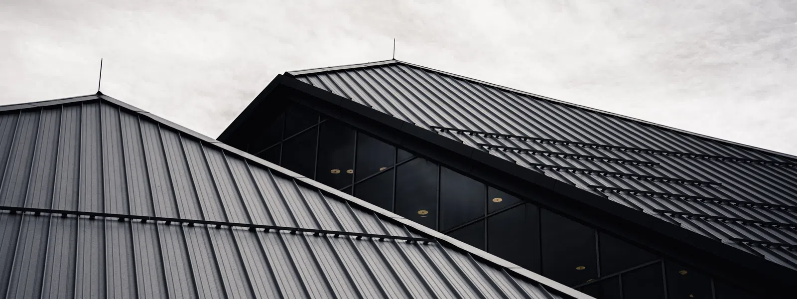 Modern architecture featuring angular metal roofs against a moody sky..