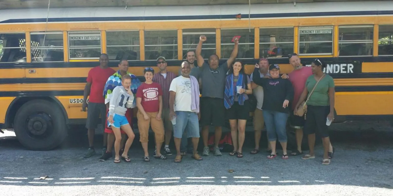 a group of people standing in front of a school bus