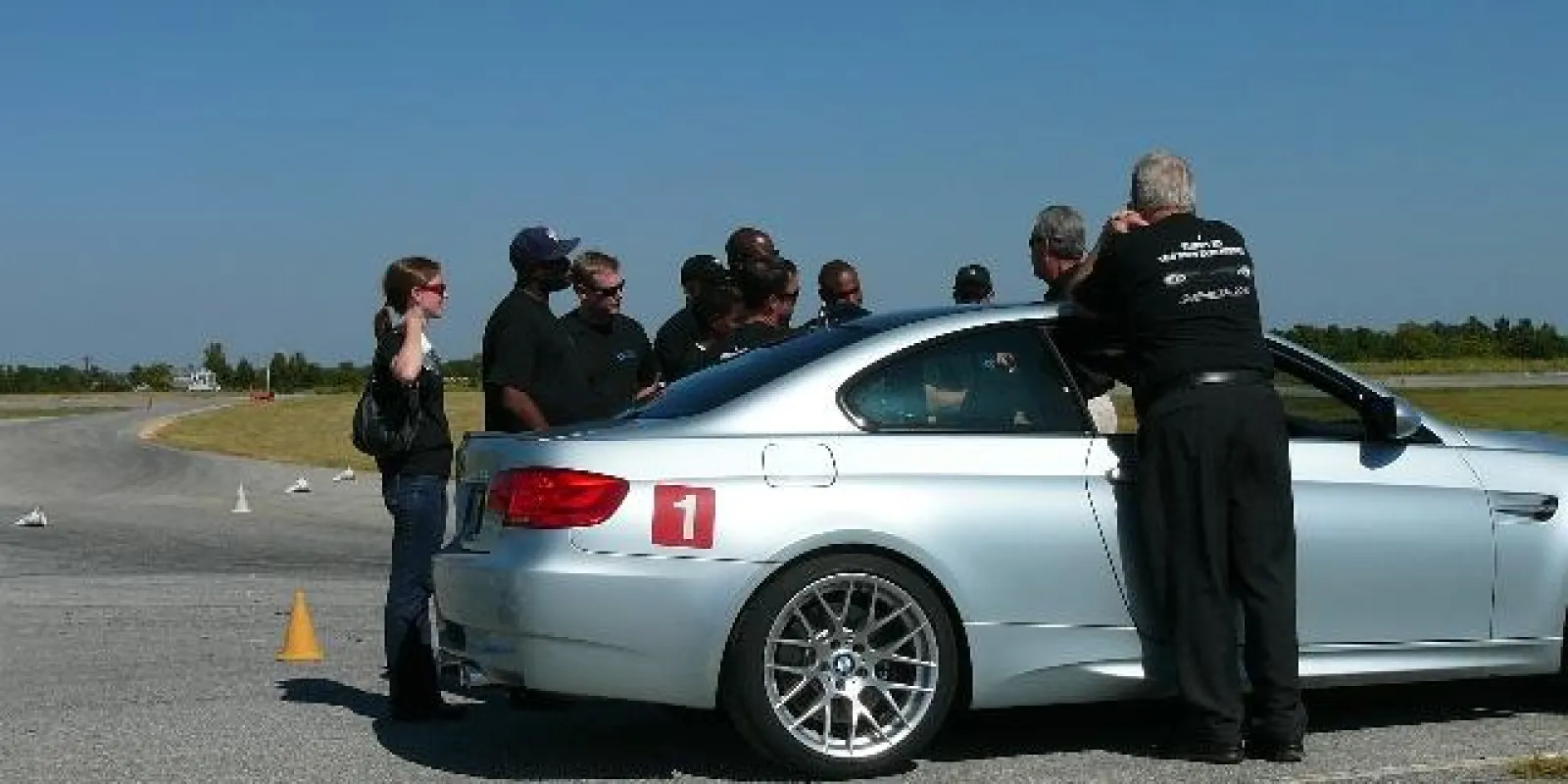 people standing around a car on a test track