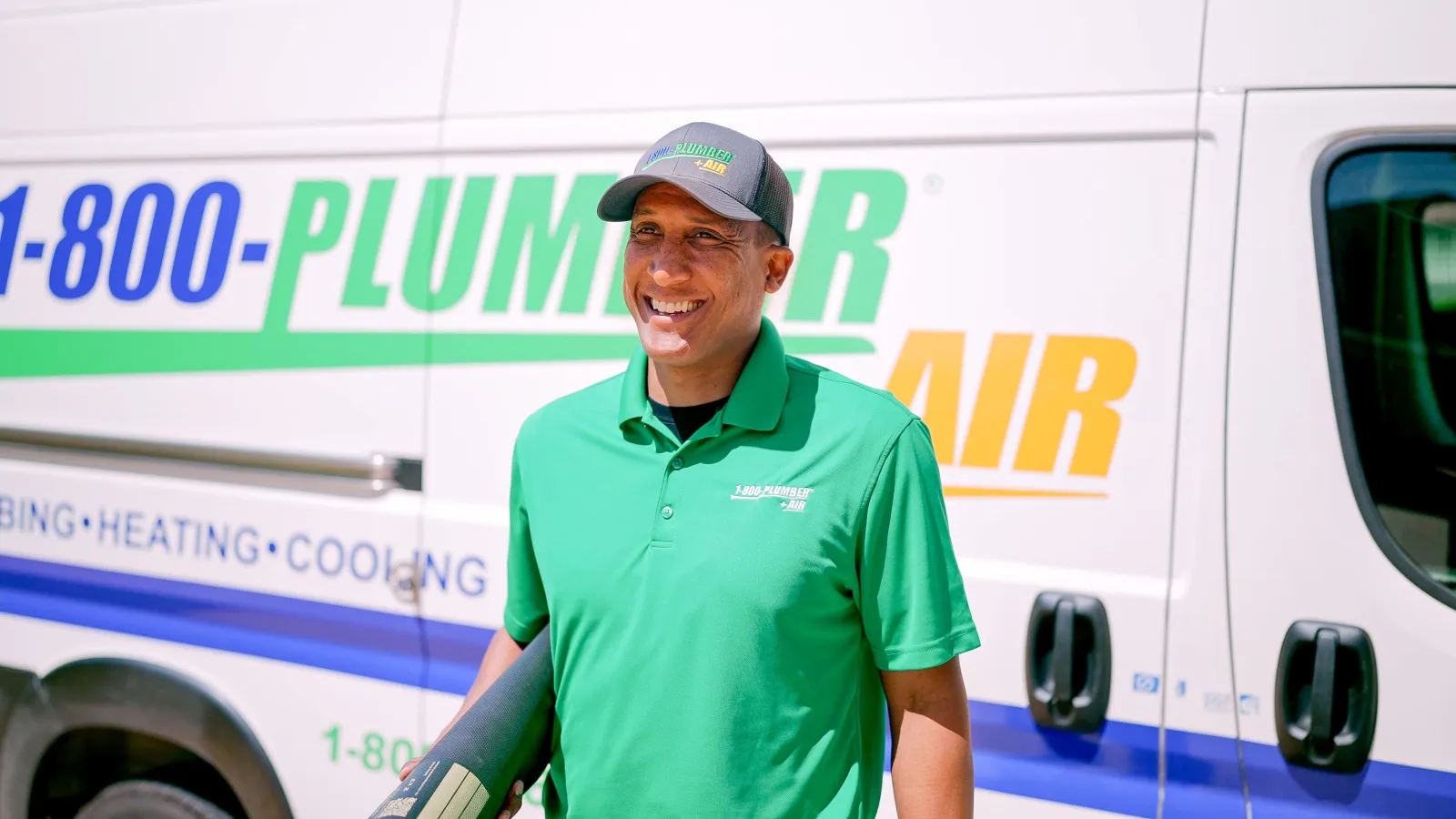 A Raleigh heat pump technician in front of a 1-800-Plumber +Air van