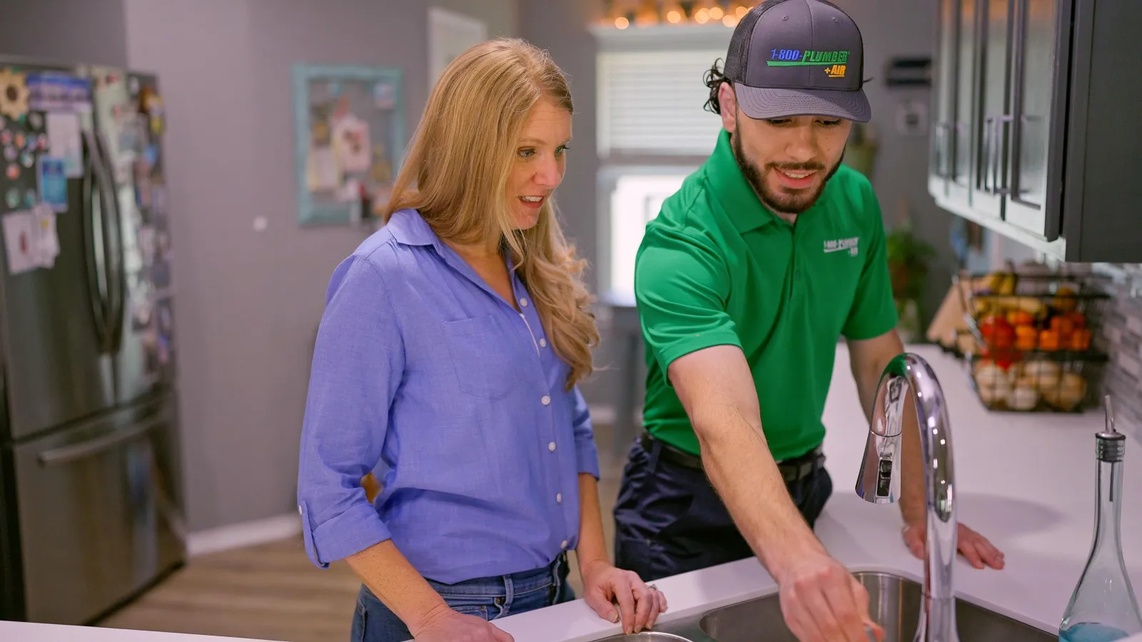 a Houston plumber and a woman standing in front of a sink
