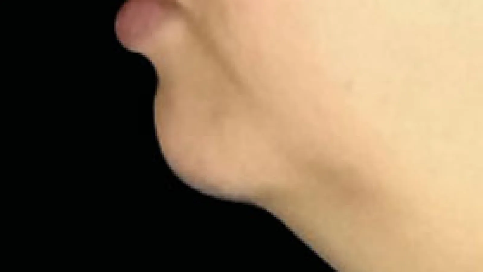 Side profile of a person's lower face showing the chin and neck against a black background