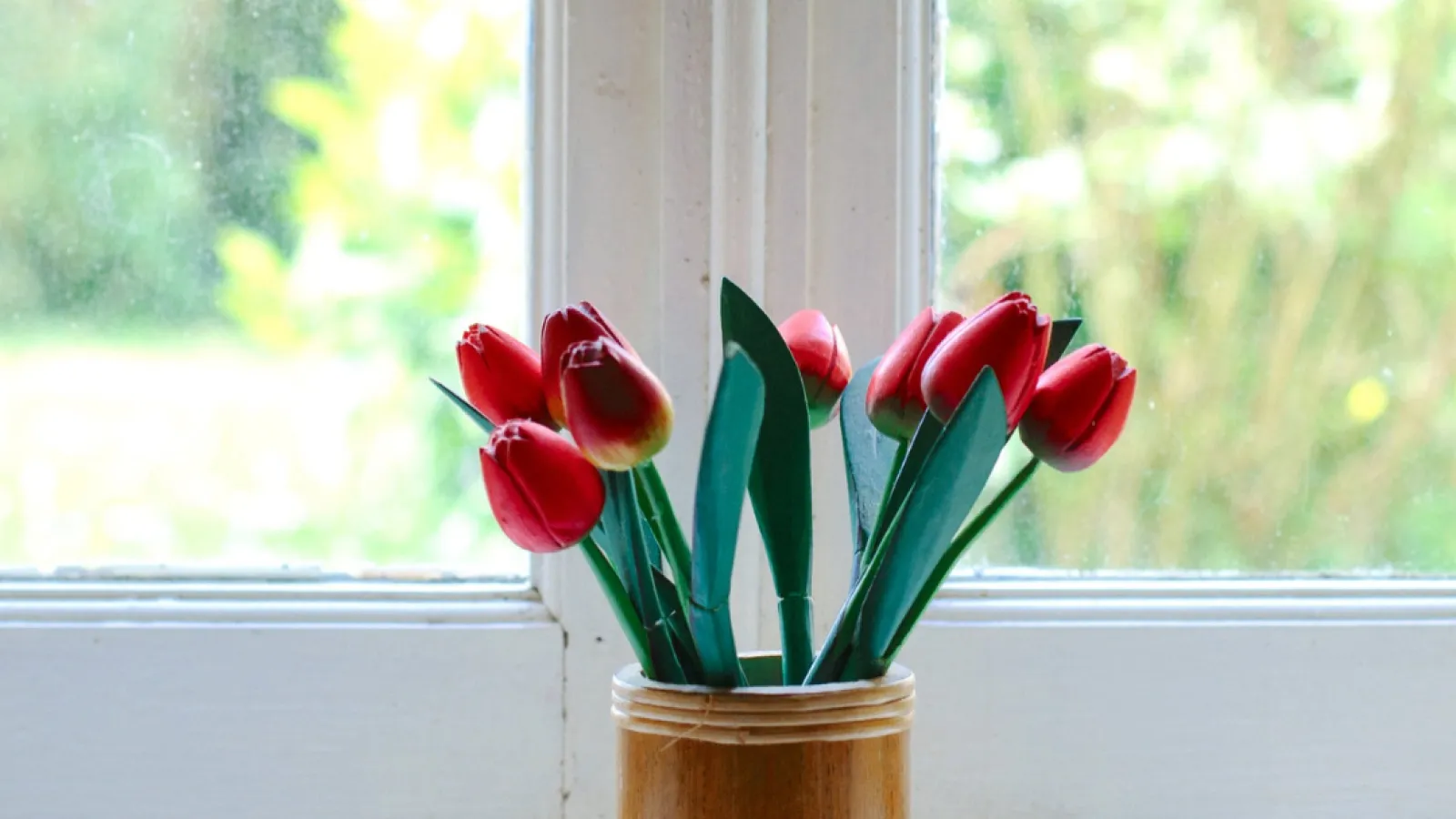a vase filled with flowers sitting on a ledge in front of a window