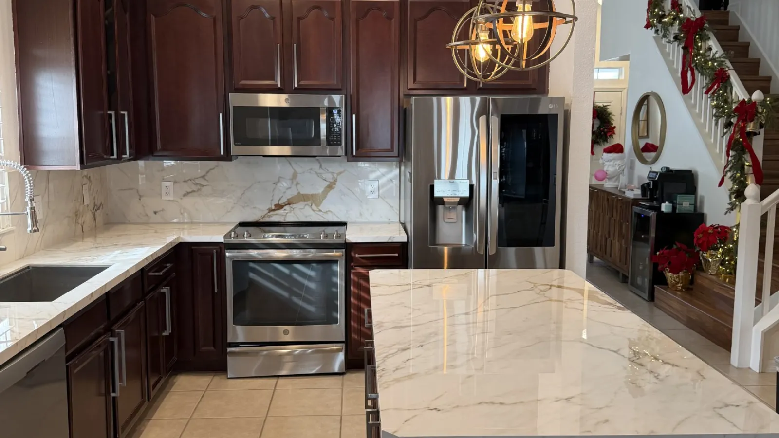 Modern kitchen with dark wood cabinets, marble countertops, stainless steel appliances, and decorative pendant lights.