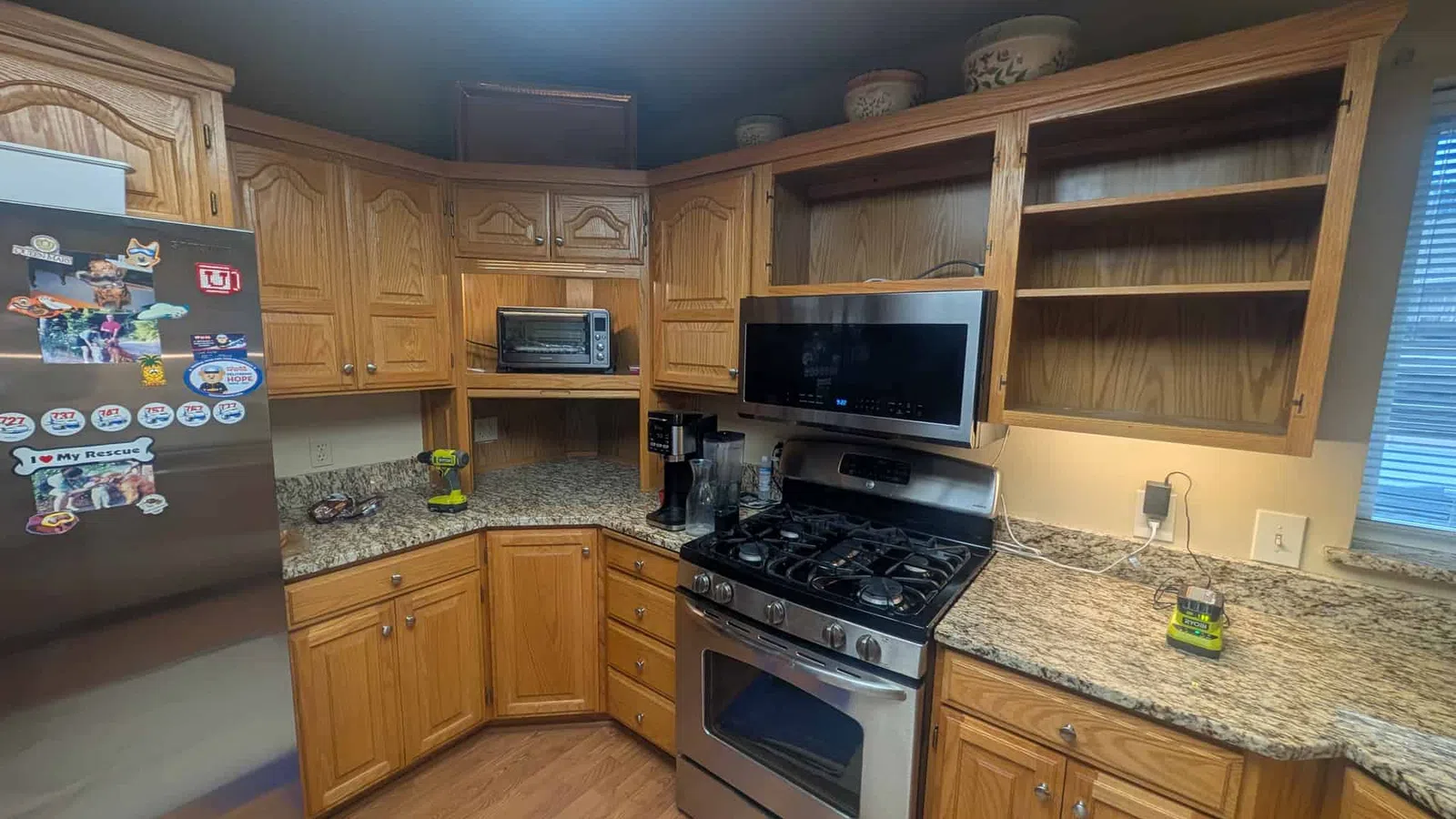 Modern kitchen with wooden cabinets, granite countertops, stainless steel stove and refrigerator with magnets.