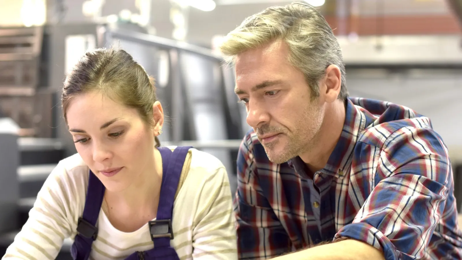 A male and female working in front of a Printing Press