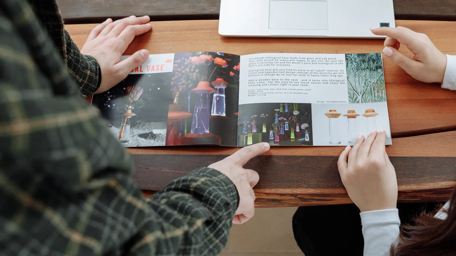 A man and a woman sitting at a table looking through a Printed Brochure