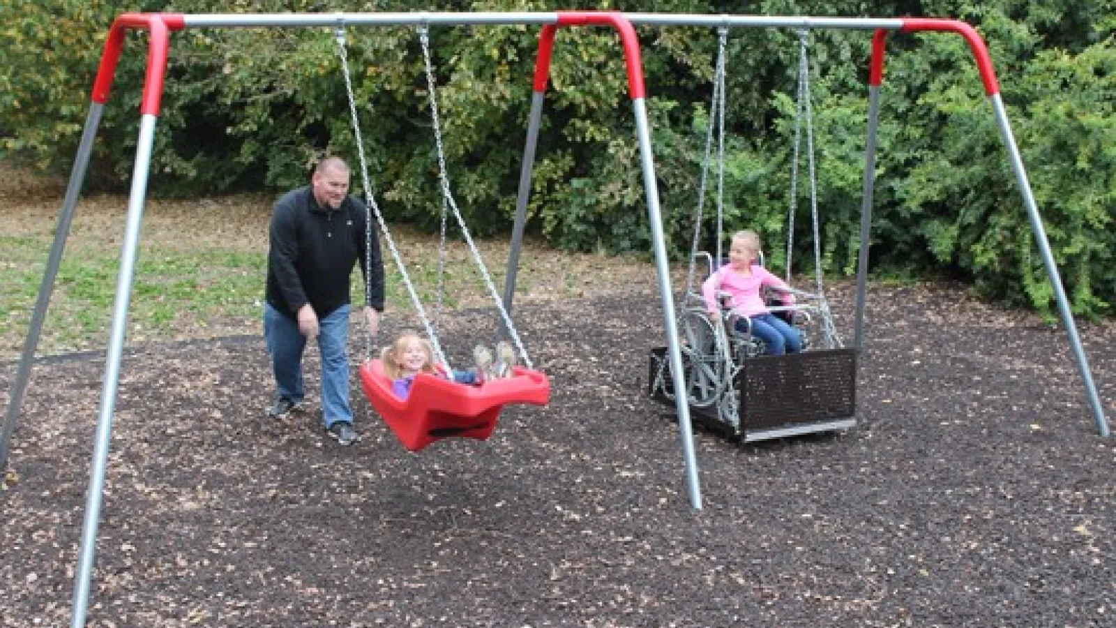 a person and two children on a swing set
