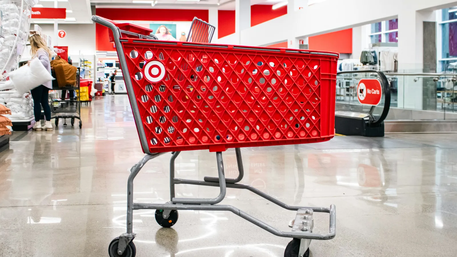 Red Target shopping cart inside a brightly lit store with polished floors and shoppers in the background