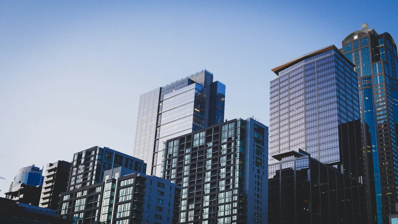 Modern skyscrapers and office buildings against a clear blue sky in an urban cityscape.