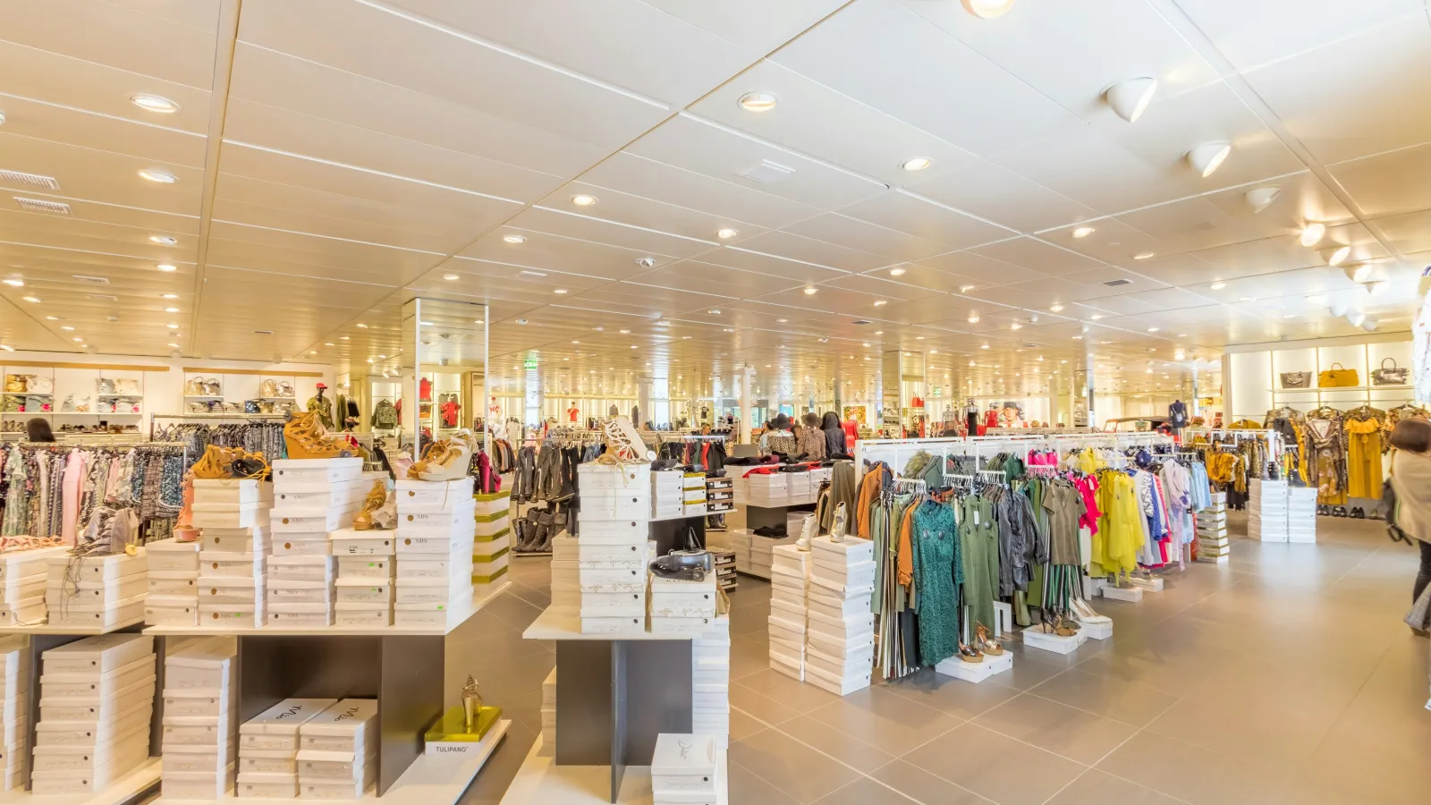 Bright clothing store interior with racks of colorful outfits and stacks of shoe boxes on display