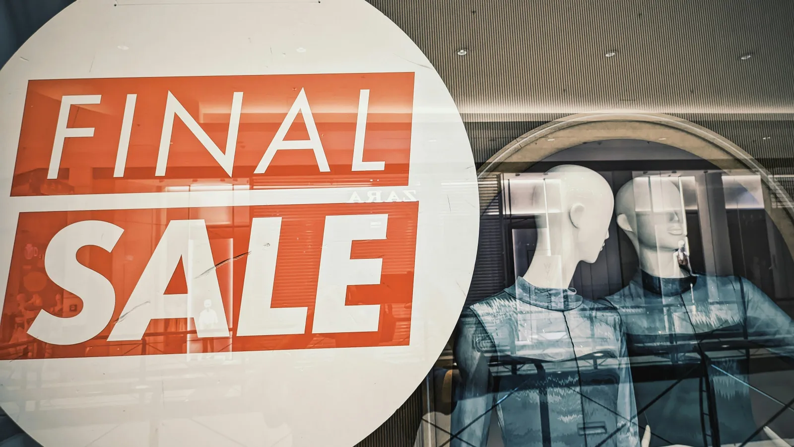 Final sale sign displayed in a store window with two mannequins wearing blue clothing inside.
