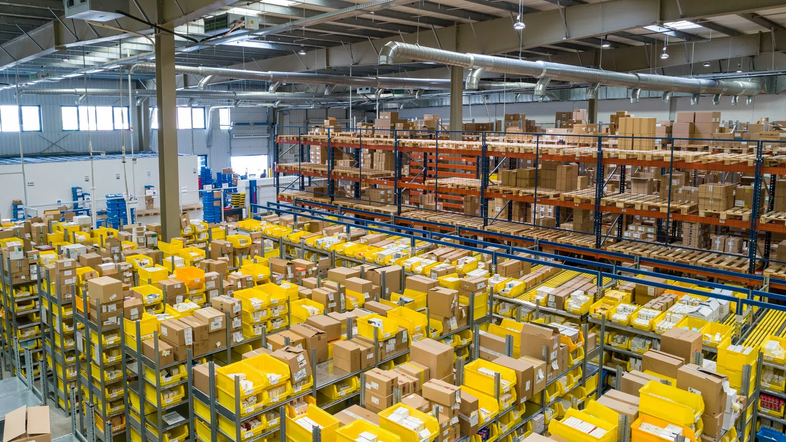 Warehouse interior with shelves filled with yellow and brown packages and organized inventory system