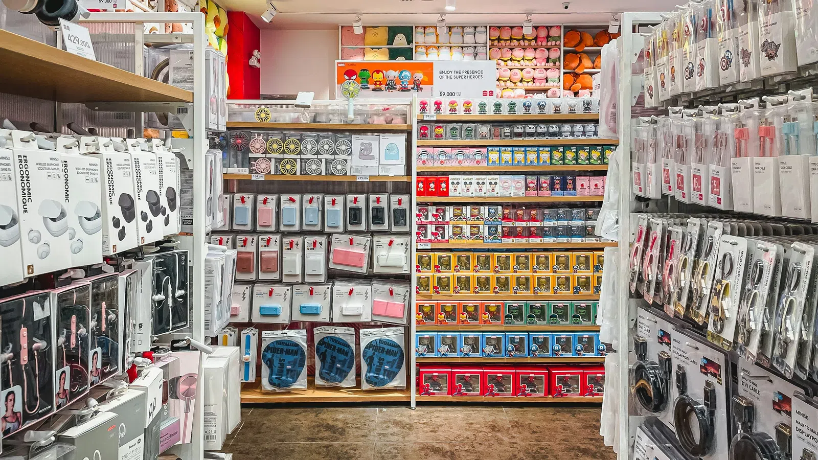 Store aisle filled with headphones, phone cases, and colorful collectible toys on shelves under bright lighting.