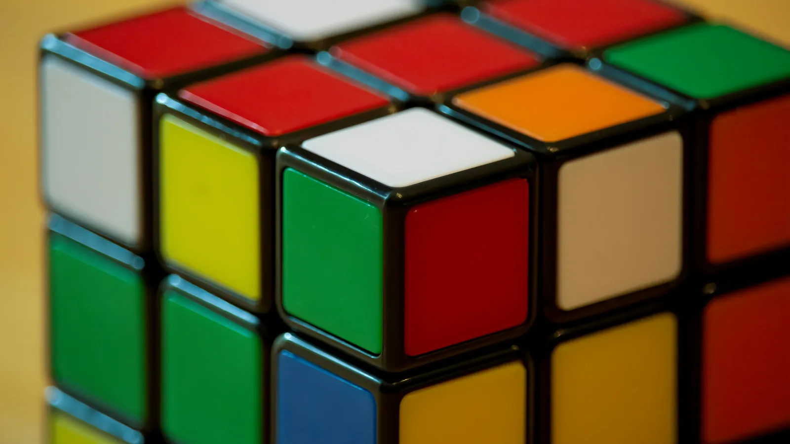 Close-up of a partially solved Rubik's Cube showing mixed colored squares including red, green, blue, white, yellow, and orange.