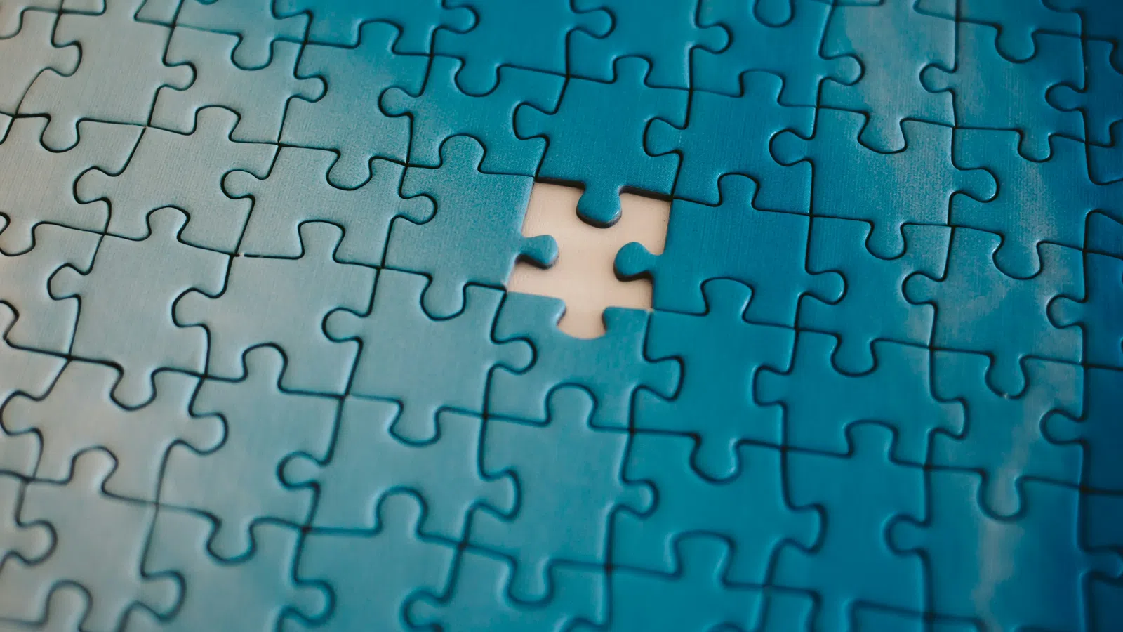 Blue puzzle pieces with one piece missing, highlighting an incomplete section on a smooth surface.