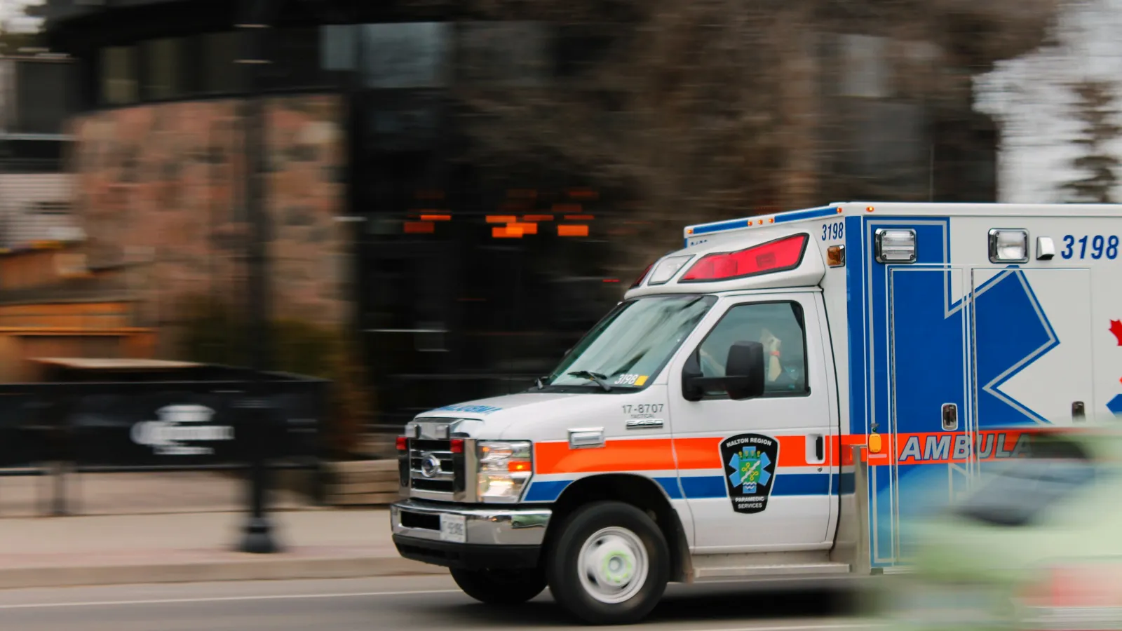 Emergency ambulance with flashing lights speeding down an urban street during daytime rapid response.