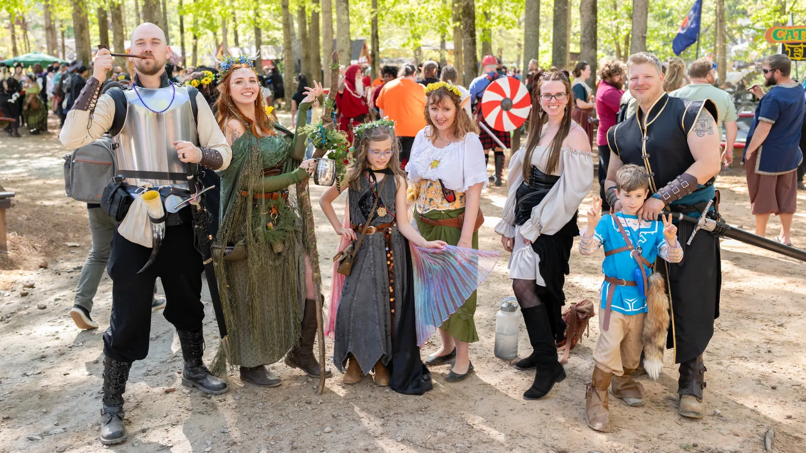 Group of people dressed in medieval and fantasy costumes posing together at an outdoor festival