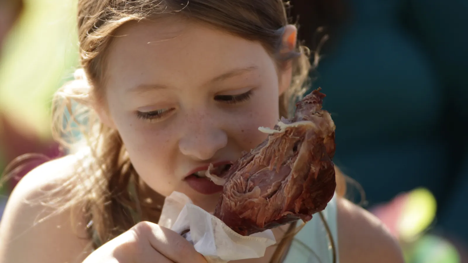 a girl eating a piece of meat