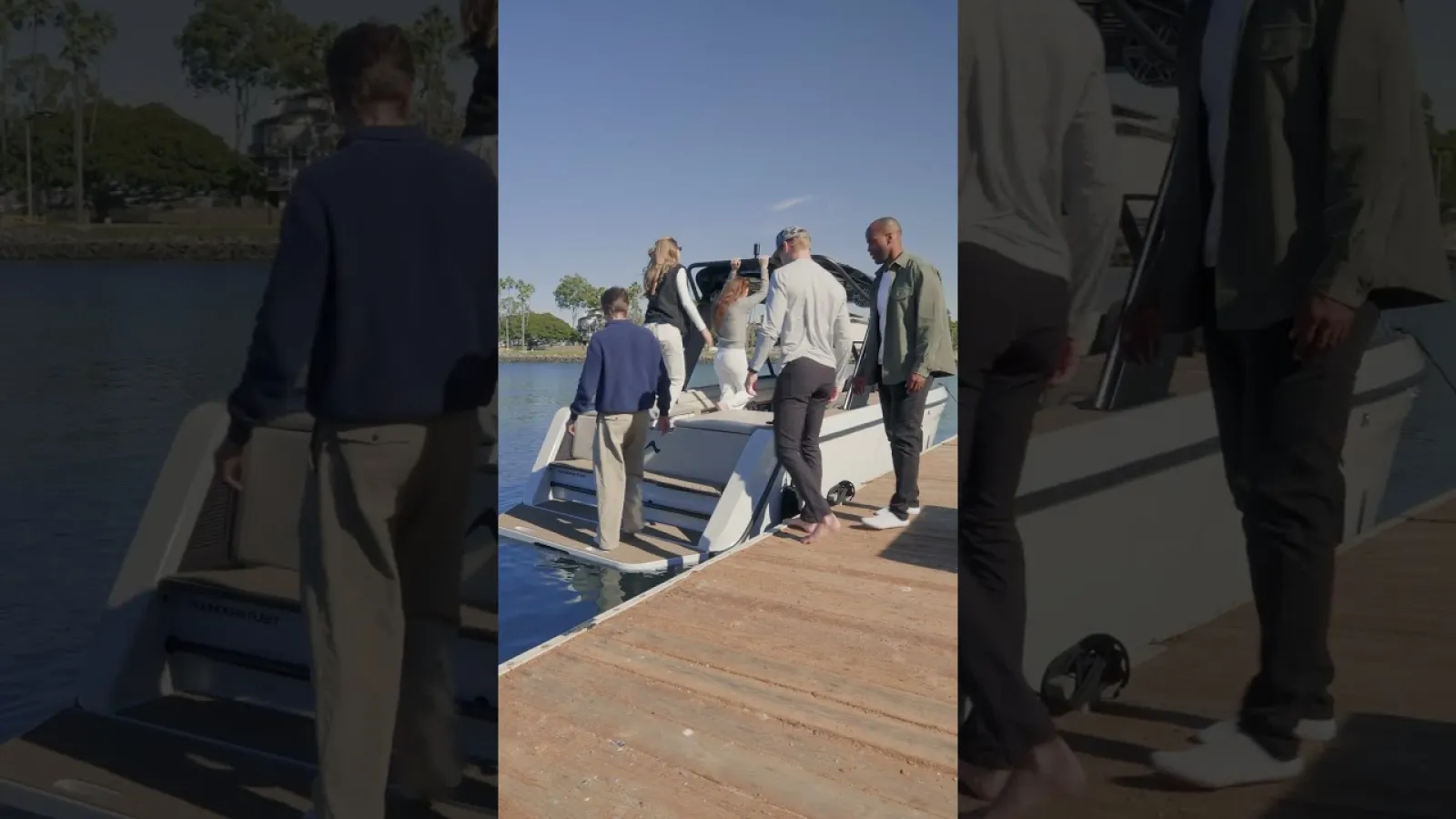 Group of people boarding a white boat at a wooden dock on a sunny day by the water.