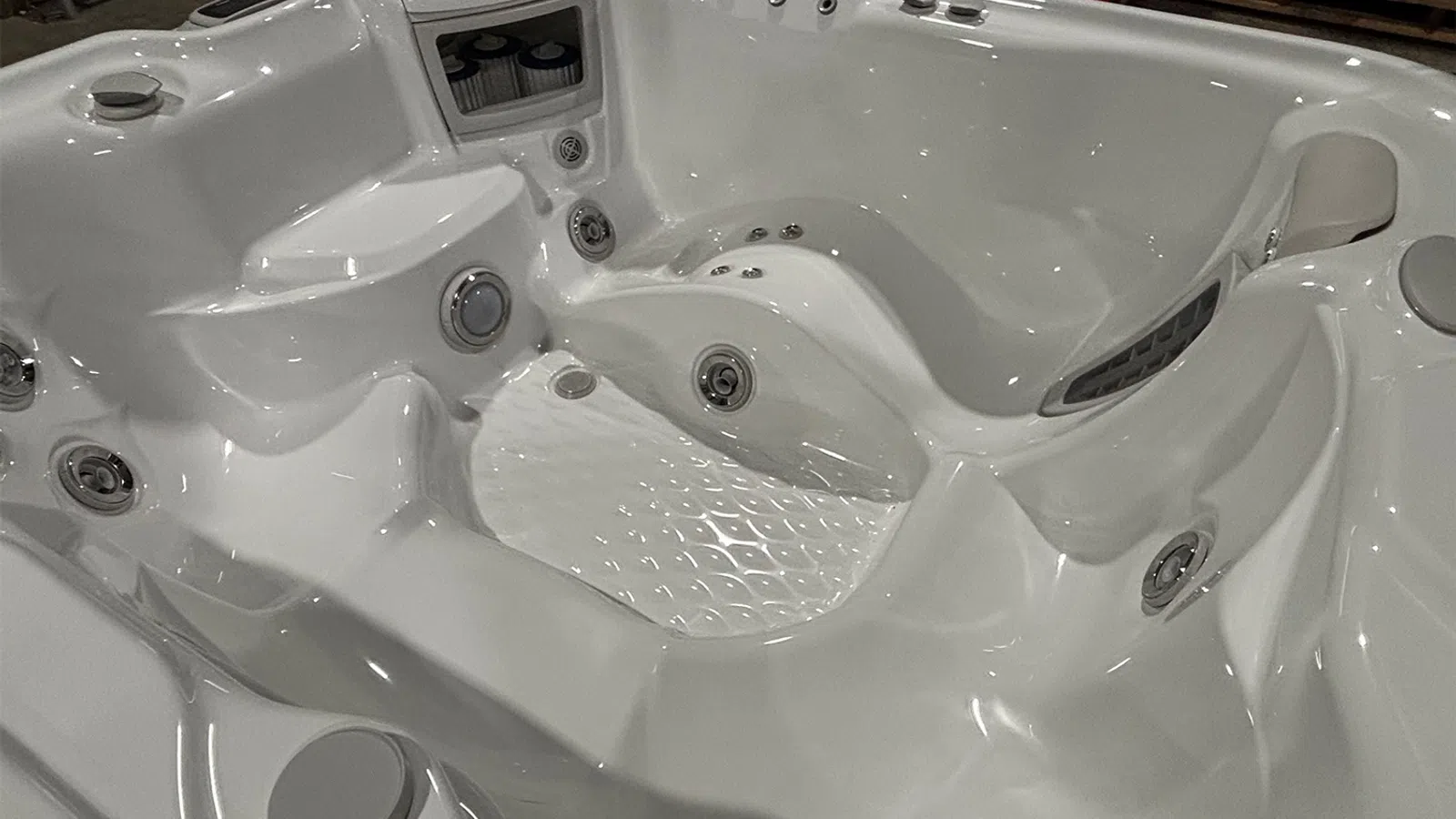 Close-up of an empty white jacuzzi hot tub with multiple jets and ergonomic seating
