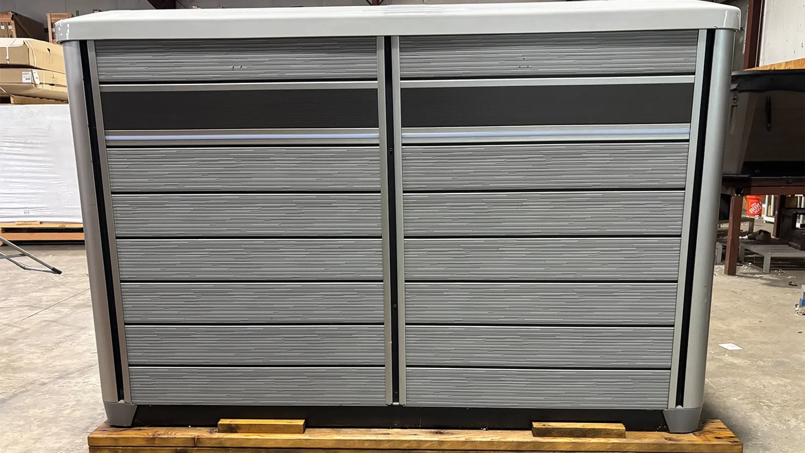 Large gray industrial storage cabinet with multiple drawers on wooden pallet in warehouse setting