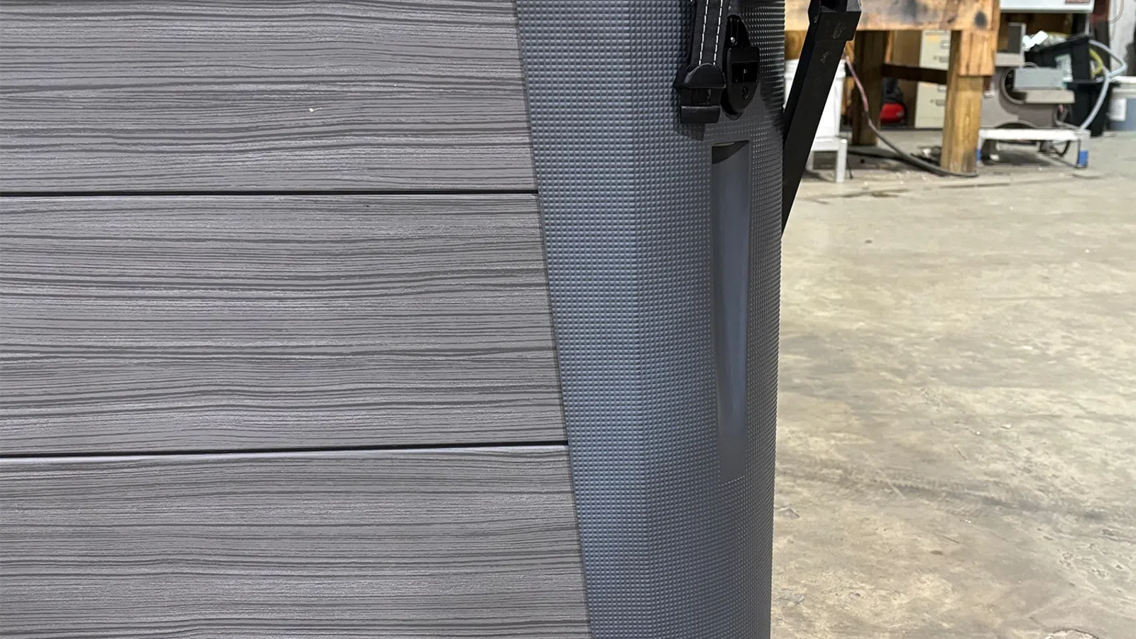 Close-up of a gray textured cooler with a latch on the side in a workshop setting