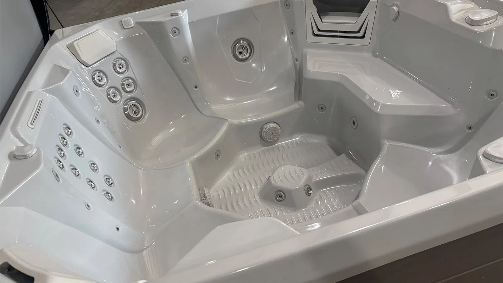 White modern hot tub with multiple seating areas and built-in water jets for hydrotherapy and relaxation.