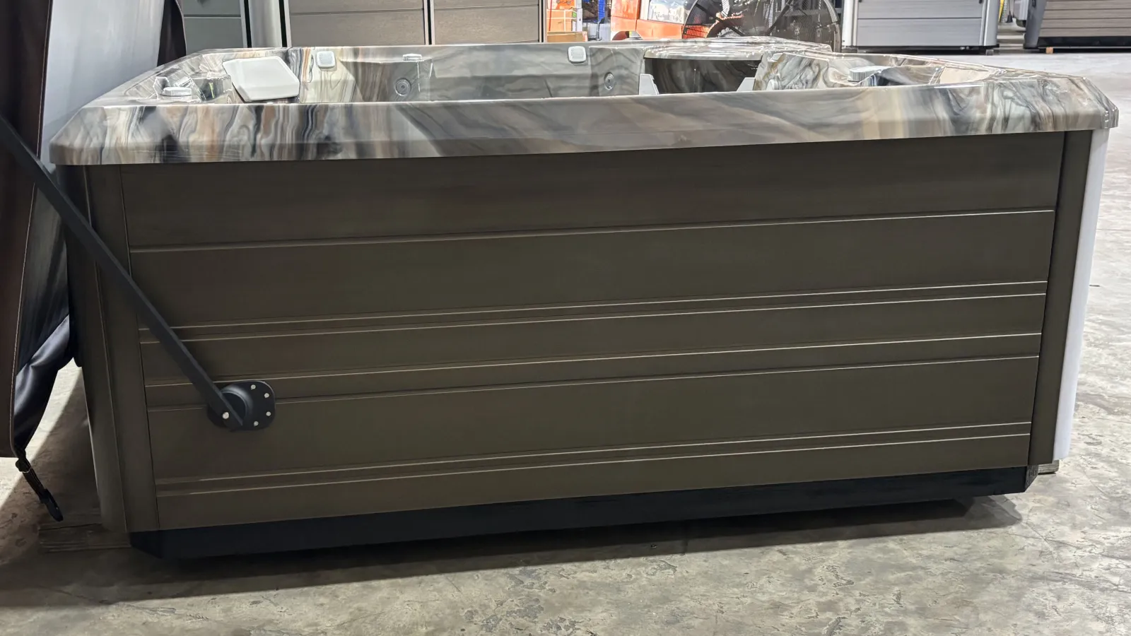 Modern rectangular hot tub with a marble-patterned interior and brown wooden exterior panels indoors.