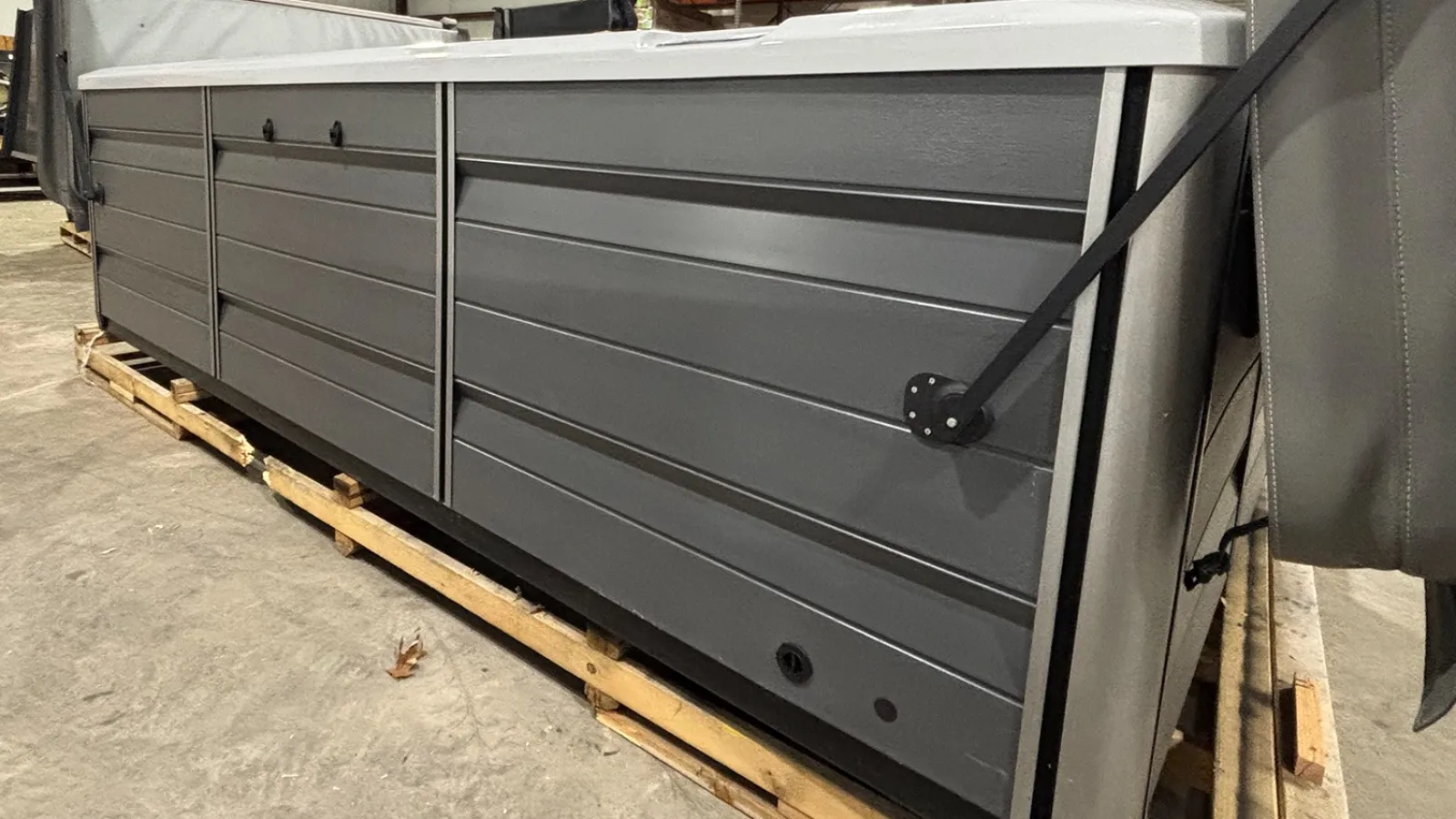 Gray modular storage unit with black hardware resting on wooden pallets in warehouse setting